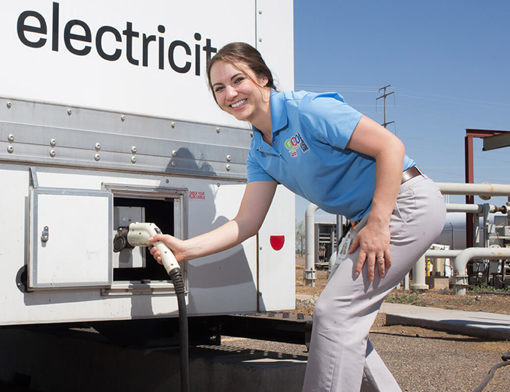 Woman smiling to camera while charging her electric van